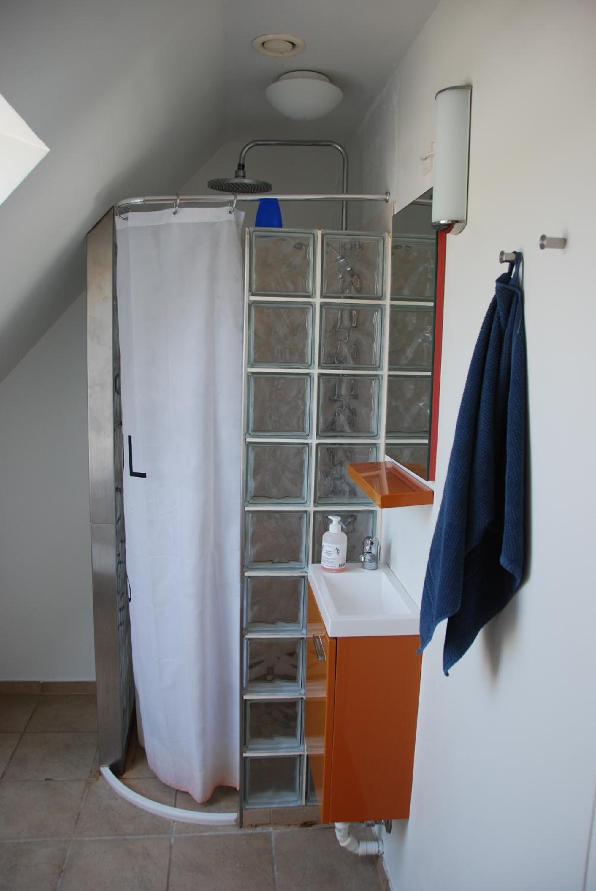 A shower with a glass enclosure, a white sink with a blue towel, and a tiled shower area.