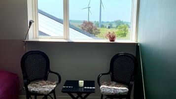 A small room with two chairs, a table, and a window overlooking wind turbines.