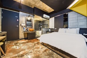 Moderni hotellihuone, jossa on suuri sänky, kylpyammeella varustettu kylpyhuone ja pieni työpöytä, jossa on pesuallas.