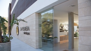 A modern building with a glass entrance, a sign reading "SAPEDRA sales & spa", and potted plants outside.
