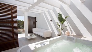 Un espacio al aire libre moderno con un jacuzzi, mobiliario blanco y vistas del paisaje circundante.