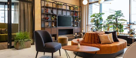 A modern living room with a sofa, chairs, a TV, and a bookshelf.