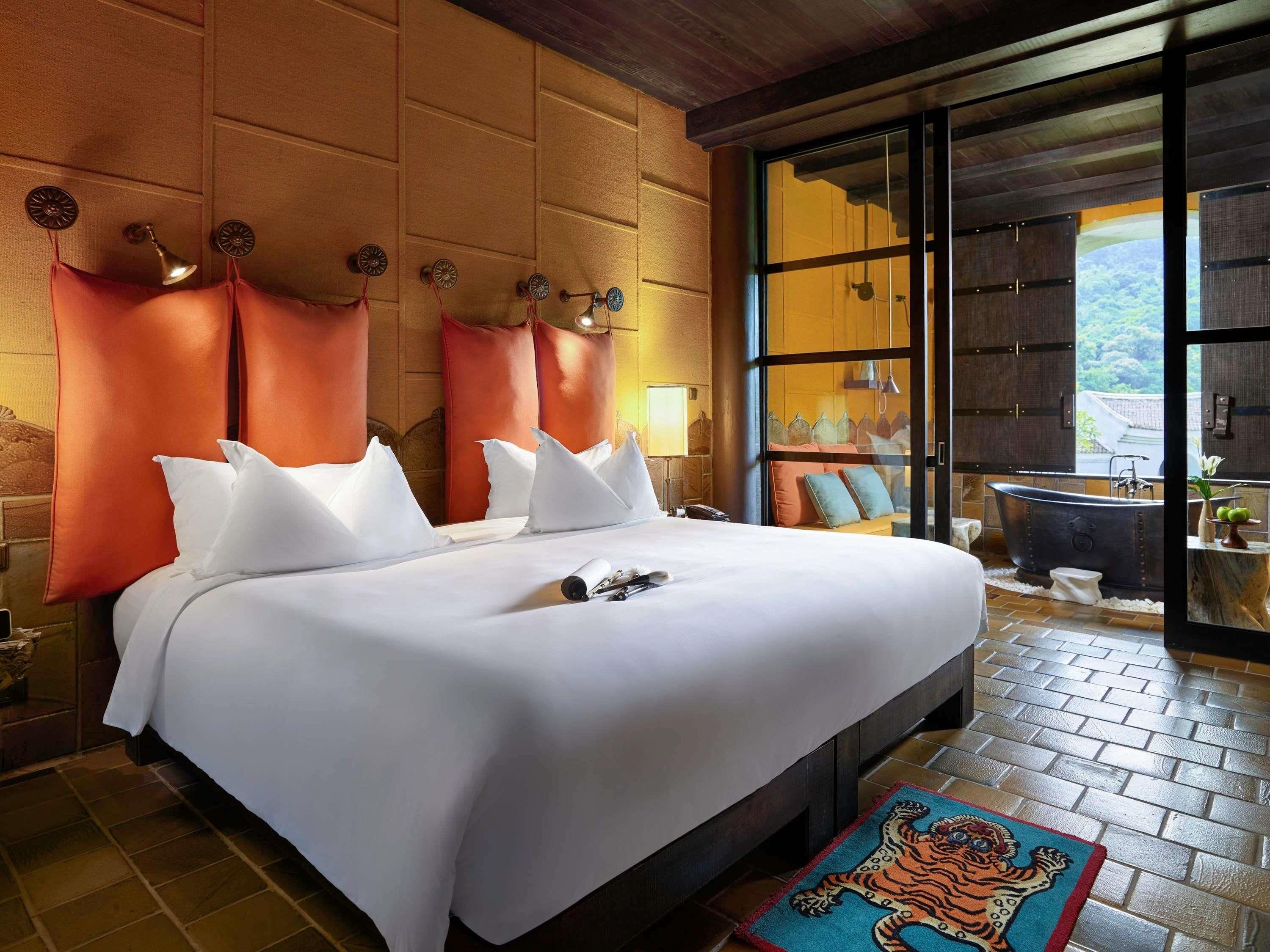 A hotel room with a large bed, a bathtub, and a view of the outdoors.