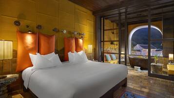 A hotel room with a large bed, a view through a glass wall, and a wooden ceiling.