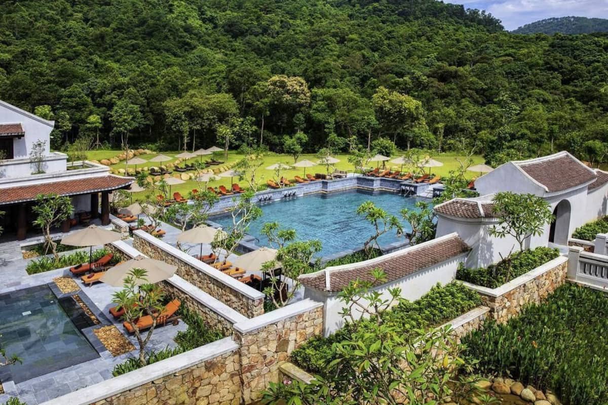 Ein Resort mit Swimmingpool, Liegebereichen und Blick auf einen üppigen Wald.