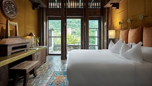 Un'ampia camera da letto con un letto grande, mobili in legno e vista sul verde attraverso ampie finestre.