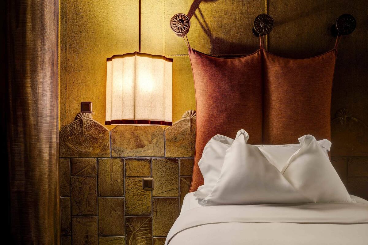 Ein Hotelzimmer mit einem Bett, einer Wandlampe und einer strukturierten Wand.