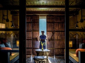 A room with a large window, a wooden floor, and a person standing by the window. - LEGACY YEN TU RESORT & RETREAT - MGALLERY COLLECTION (Yen Tu)
