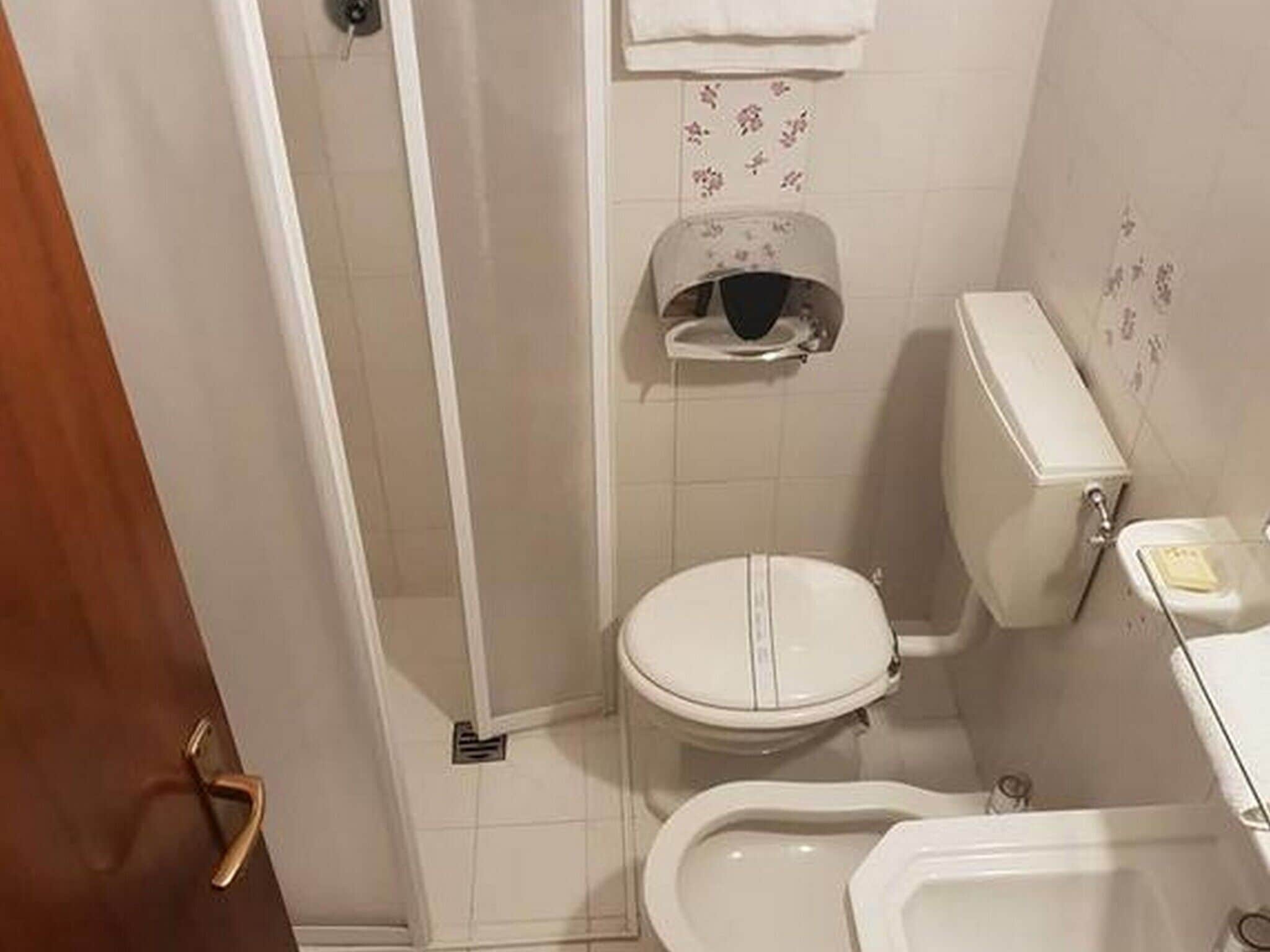 A small bathroom with a toilet, bidet, and a shower area.