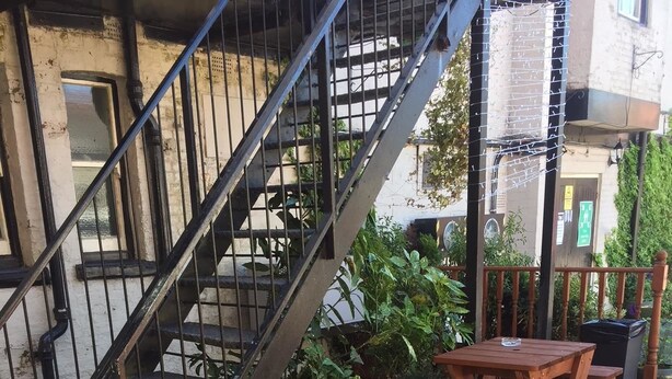 A wooden deck with a metal staircase leading to a building. There are two wooden tables and chairs on the deck. - The George Inn (Barton-upon-Humber)