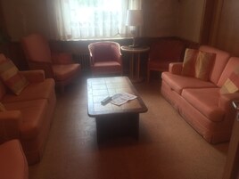 Una sala de estar con una mesa de centro, dos sofás, una silla y una lámpara.
