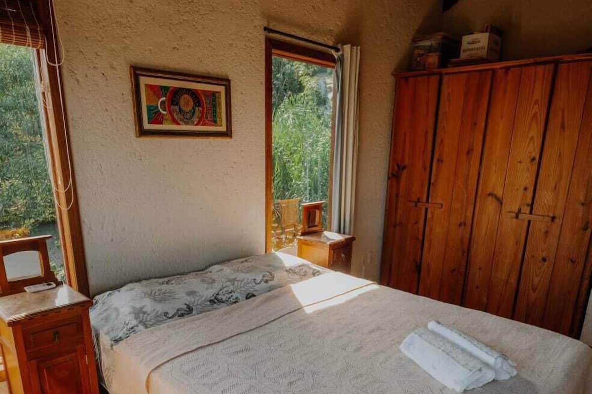 Een slaapkamer met een bed, een houten garderobe en een raam.