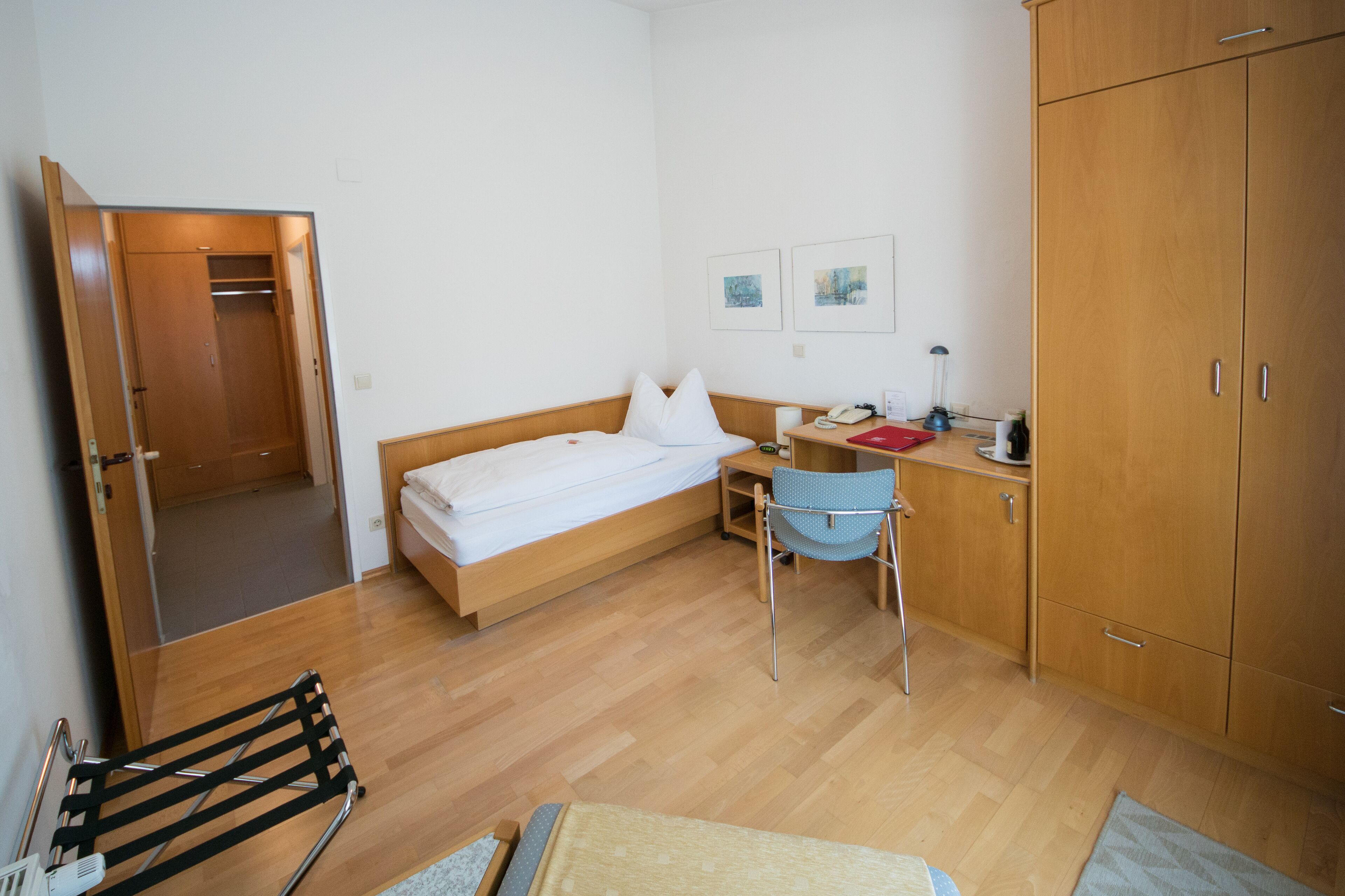 Un dormitorio con cama, escritorio, silla, armario y baño.