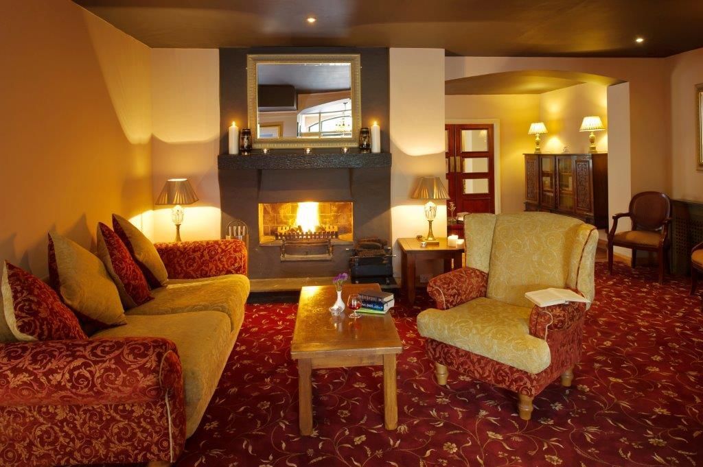 Una habitación con chimenea, dos sofás, una mesa y una silla.