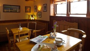 Un rincón comedor acogedor con muebles de madera, una mesa con comida, una taza y un florero con flores.