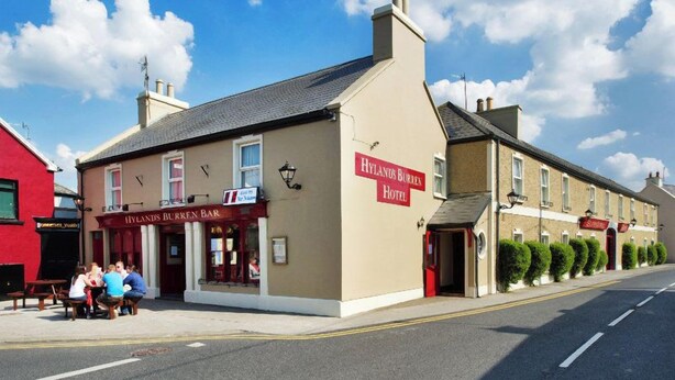 Un edificio de dos pisos con un letrero que indica 'Hylands Burren Bar' y 'Hylands Burren Hotel' en la planta baja.