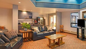 A modern living room with a leather sofa, a coffee table, and a kitchen area in the background. - Travelodge Rapid City (Rapid City)