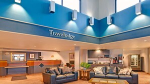 A Travelodge lobby with two leather sofas, a coffee machine, and a reception desk. - Travelodge Rapid City (Rapid City)
