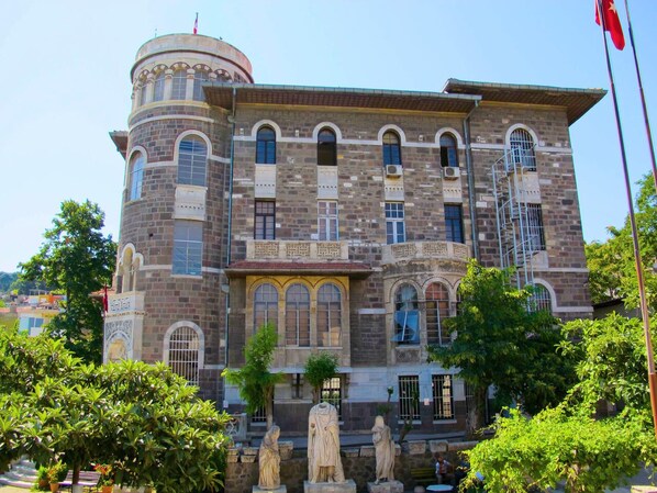A historic building with a central dome, arched windows, and statues in front. - Ada Apart (Izmir)