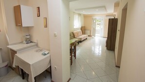 Un amplio salón con sofá, mesa de comedor y zona de cocina con refrigerador y cafetera.