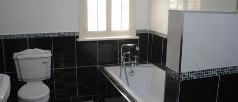 A bathroom with a toilet, a bathtub, and a window.