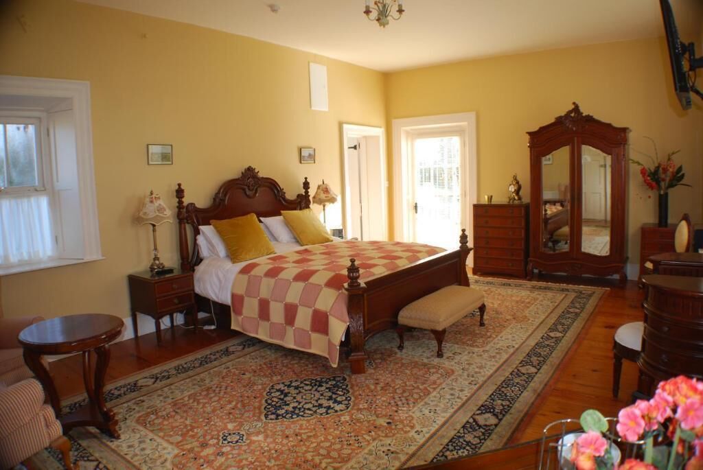 A bedroom with a large bed, a wooden dresser, a mirror, and a small table.
