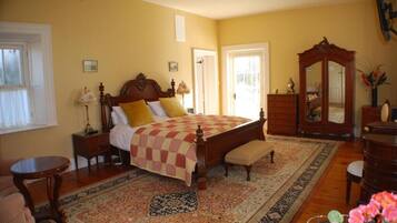 A bedroom with a large bed, a wooden dresser, a mirror, and a small table.