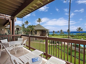A balcony with a view of the ocean and palm trees.