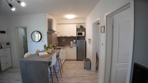 A compact kitchen with a central island, white cabinets, a microwave, and a refrigerator.