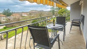 Un balcón con dos mesas redondas y sillas, vista al campo y barandilla.