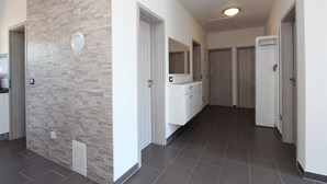 A hallway with a stone accent wall, a white dresser with a mirror, and a tiled floor. - MONDELACO Three-Bedroom Apartment (Rovinj)