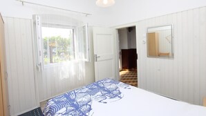 Une chambre à coucher avec un lit, une fenêtre, une porte et un miroir.