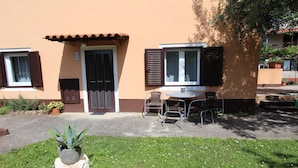 Un bâtiment doté d’une porte, de fenêtres et d’une petite table avec des chaises à l’extérieur.