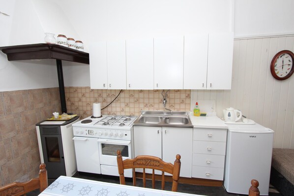 Una cocina compacta con armarios blancos, estufa, lavaplatos y refrigerador.