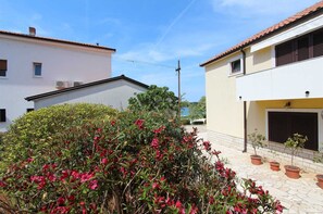 Un quartier résidentiel avec des maisons à deux étages, une cour dallée et des plantes en pot.
