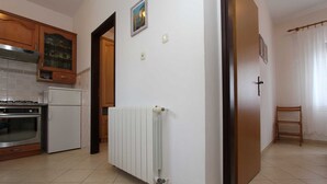 Une cuisine équipée d’une cuisinière, d’un four et d’un réfrigérateur, d’un radiateur blanc et de meubles de rangement en bois.