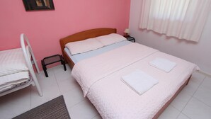 Ein Schlafzimmer mit einem Einzelbett, einem Nachttisch, einem Sessel und einem Wandbild.