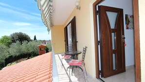 Ein Balkon mit Fliesenboden, einem Tisch mit Stühlen und einer Tür mit Fenster.