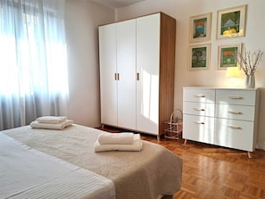 Un dormitorio con cama, armario, cómoda y pared decorada con marcos.