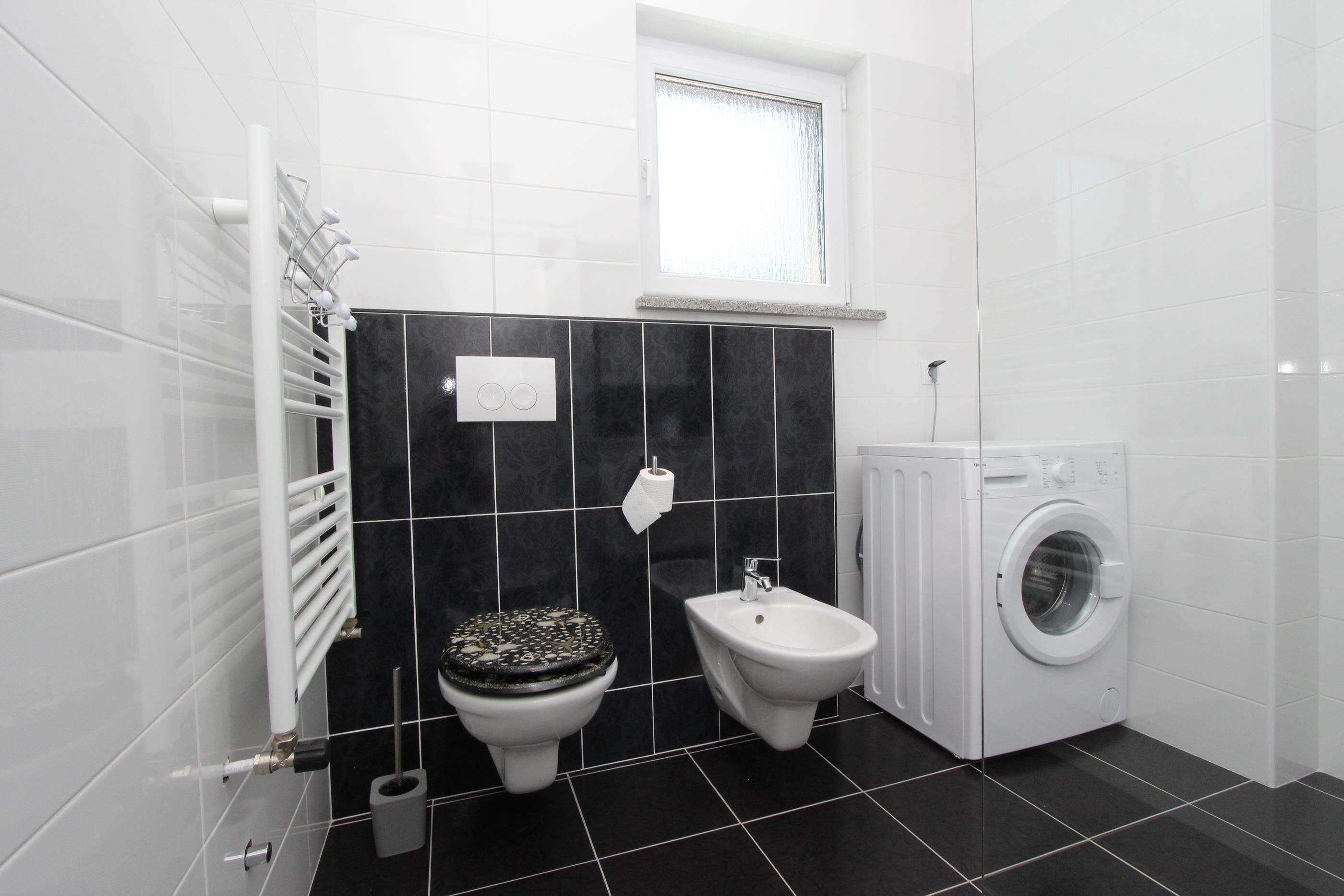 A bathroom with a toilet, bidet, and washing machine.