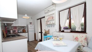 Una cocina con armarios blancos, una estufa y un comedor con una mesa preparada para dos.
