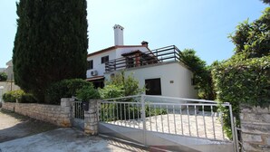 Una casa de dos pisos con balcón, paredes de piedra y un portón.