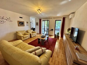 A living room with a sofa, a coffee table, a TV, and a fireplace. - ADRI Two-Bedroom Apartment (Rovinj)