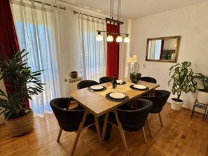 A dining area with a wooden table, black chairs, and potted plants. - ADRI Two-Bedroom Apartment (Rovinj)