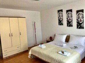 Relax in this inviting space with a comfortable bed, ample storage in the wardrobe, and a convenient nightstand with a lamp and book.