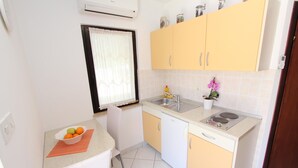 A compact kitchen with a sink, stove, and a bowl of fruit on the counter. - PATAJ One-Bedroom Apartment with Terrace 3 (Rovinj)