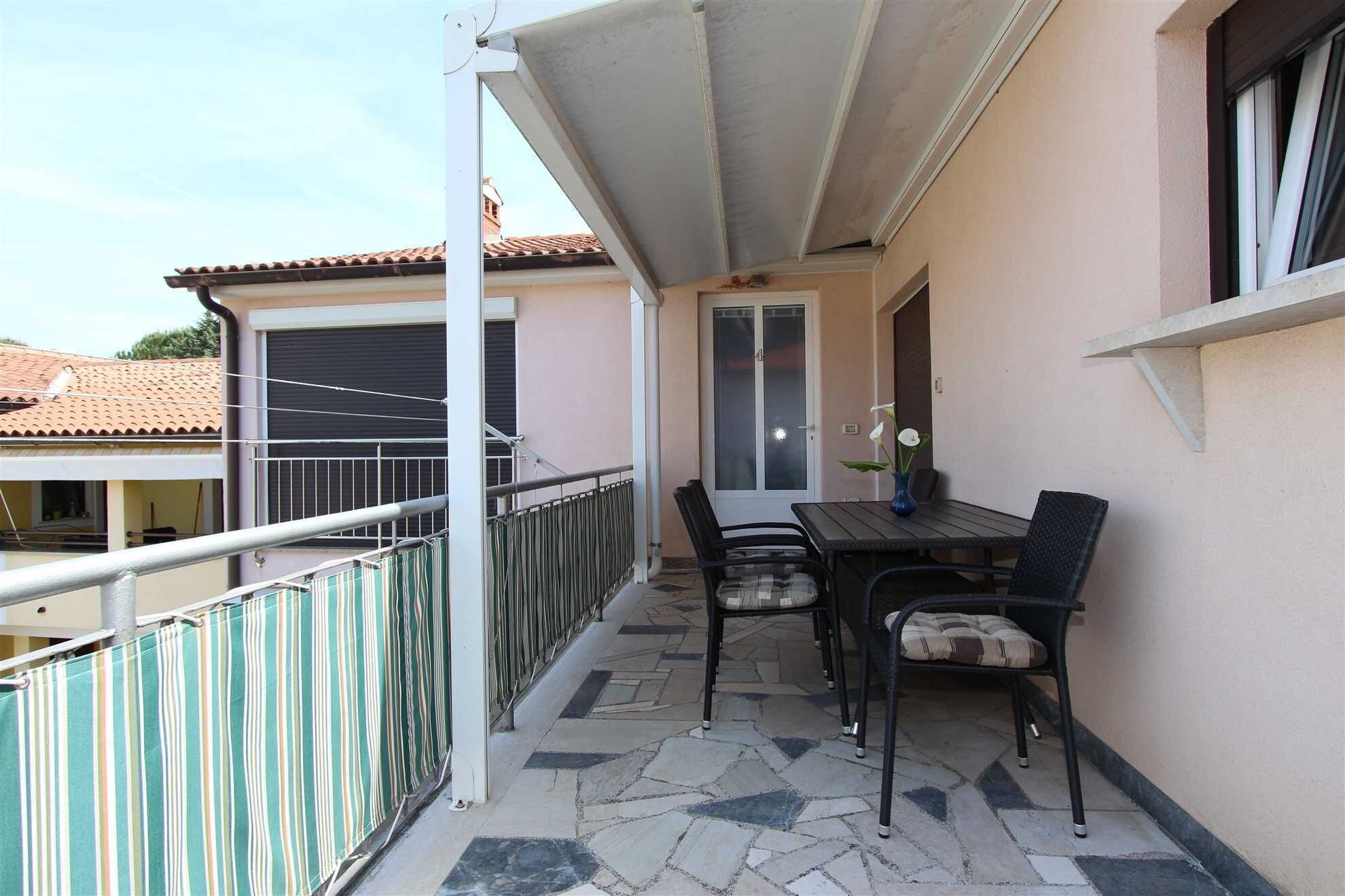 Un balcon avec une table et des chaises, une porte et une fenêtre.
