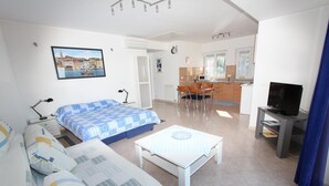 Ein modernes Hotelzimmer mit Bett, Sofa und einer kleinen Essecke mit Tisch und Stühlen.