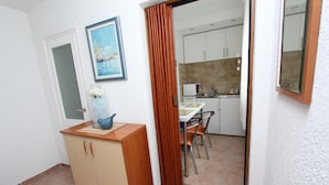 Una cocina compacta con armarios blancos, un microondas y un comedor con mesa y sillas.