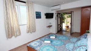 Un dormitorio con cama, cortinas, televisión y vistas al exterior.